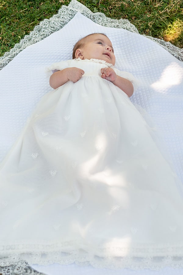 Robe de baptême traditionnelle bébé fille Gloria en tulle brodé, dentelle et mousseline de coton blanc cassé. Création française Fil de Légende. Photo de la robe portée. Photo de la robe portée par une petite fille
