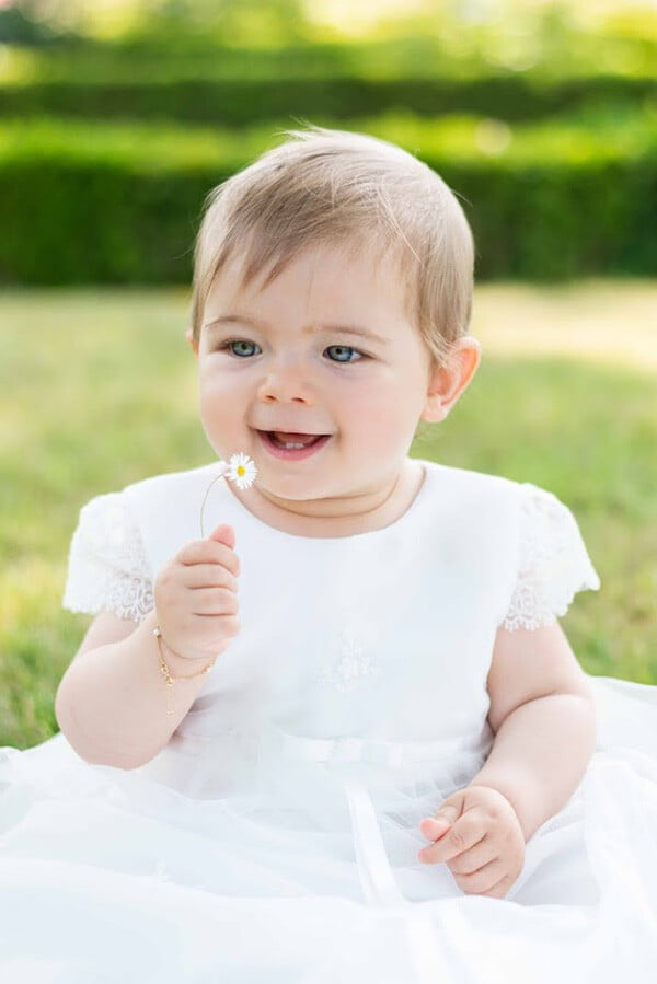 Robe baptême traditionnelle bébé fille en tulle souple brodé et dentelle doublée de satin. Modèle été manches courtes. Création française Fil de Légende.  Photo  du corsage porté par une petite fille.