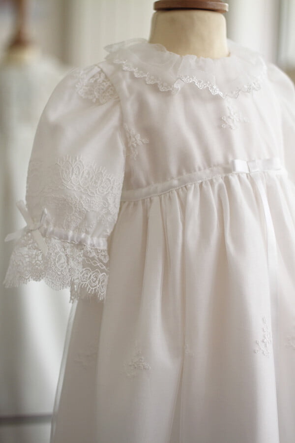 Robe de baptême traditionnelle bébé fille en tulle souple brodé et dentelle doublée coton. Création française Fil de Légende. Photo du côté de la robe.
