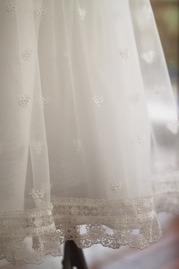 Robe de baptême traditionnelle bébé fille Gloria en tulle brodé, dentelle et mousseline de coton blanc cassé. Création française Fil de Légende. Photo des détails de la jupe.