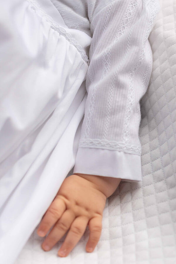 Robe traditionnelle mixte en coton blanc pour bébé fille et garçon. Corsage en coton brodé et dentelle de coton. Modèle manches longues. Création française Fil de Légende. Photo de la manche.