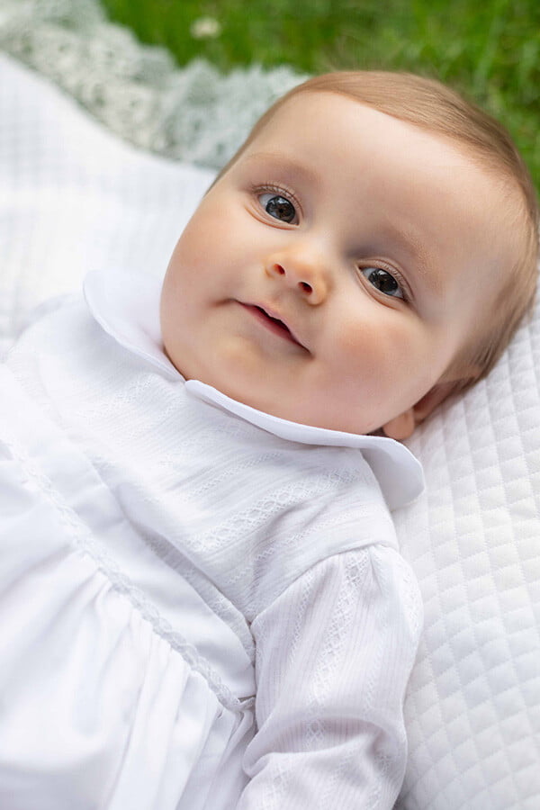 Robe traditionnelle mixte en coton blanc pour bébé fille et garçon. Corsage en coton brodé et dentelle de coton. Modèle manches longues. Création française Fil de Légende. Photo gros plan du corsage.