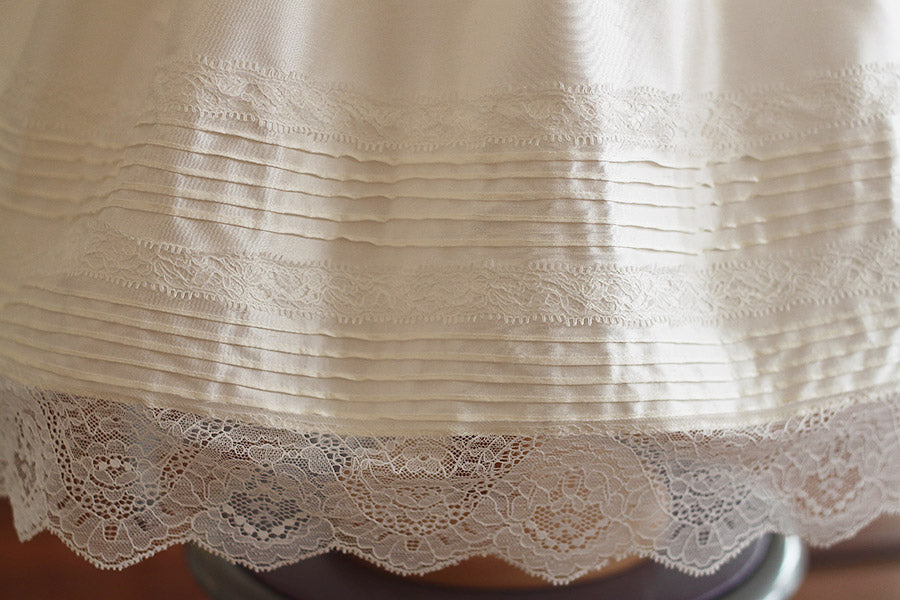 Robe de baptême et brit milah en soie française et dentelle. Cousu main en France. Photo du détail des petits plis sur le bas de la jupe.