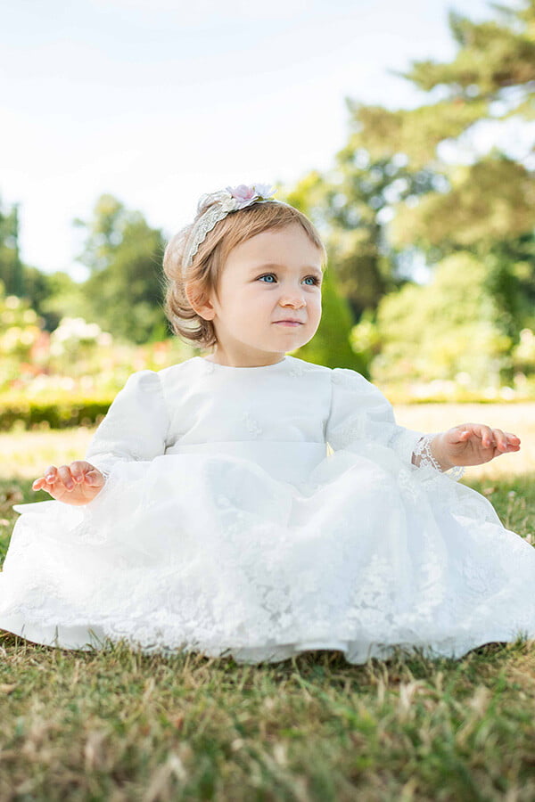 Robe de baptême et de cérémonie pour bébé et petite fille, en tulle brodé blanc cassé doublé de satin. Robe automne-hiver manches longues. Création française Fil de Légende. Photo de la robe portée par un bébé fille.