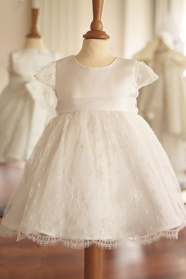 Robe de baptême ou de cérémonie pour bébé et petite fille en dentelle de Calais, doublée de satin, modèle été à manches courtes. Création Fil de Légende, disponible en ligne et en boutique à Paris–Neuilly-sur-Seine.