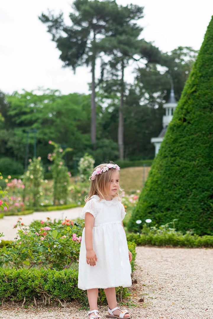 Robe de baptême bébé fille en voile plumetis doublé coton. Modèle été manches courtes. Création française Fil de Légende. Photo de robe portée par une petite fille.