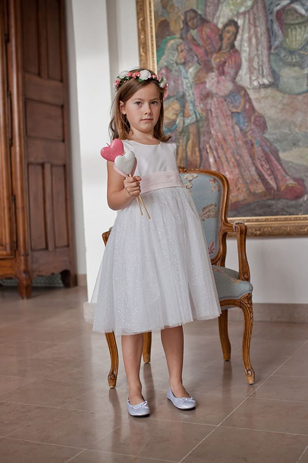 Robe cérémonie fille Lucie en taffetas et tulle pailleté blanc, ceinture rose. Photo de la robe portée par une petite fille.