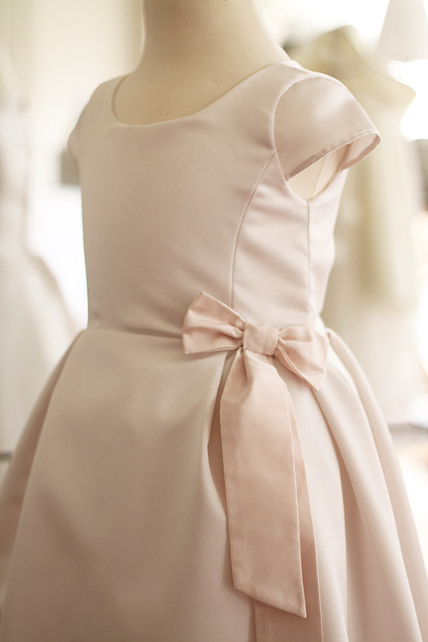 Robe longue de cérémonie fille en satin crème et noeud rose. Cousu main en France. Gros plan du noeud rose