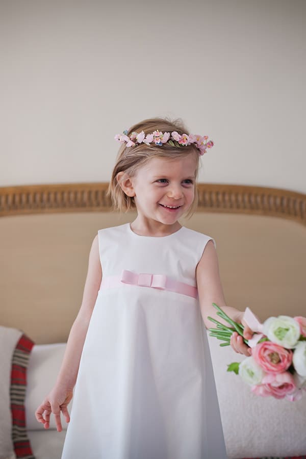 Robe trapèze cérémonie fille en coton blanc cassé et ruban rose. Photo de la robe portée par une petite fille.