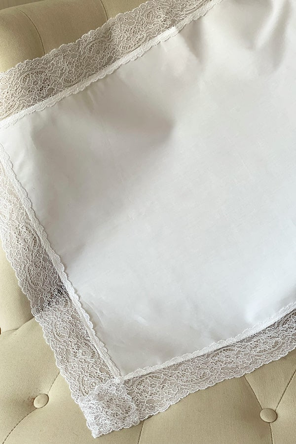 Serviette de baptême en coton blanc bordée d'un large galon de dentelle italienne blanche. Magasin Fil de Légende, Paris, Neuilly-sur-Seine.