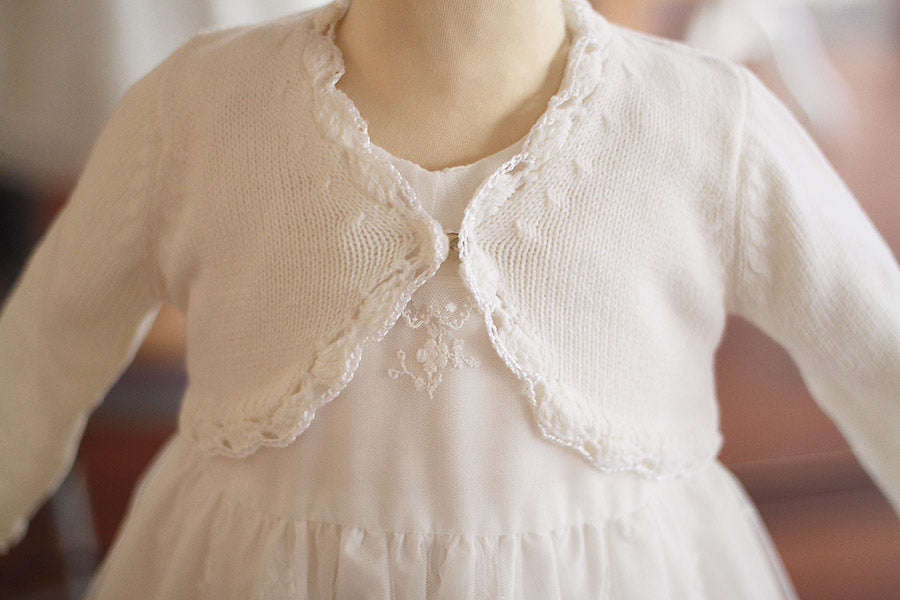 Gilet de cérémonie bébé fille en laine blanc cassé. Idéal avec robe de cérémonie bébé. Photo du gros plan du gilet.