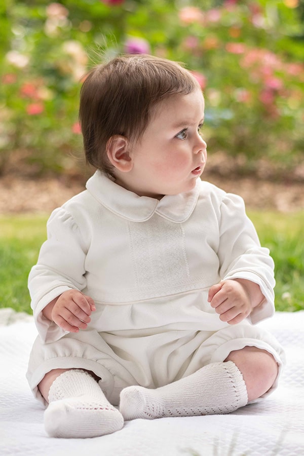 Barboteuse baptême d'hiver bébé garçon Baptiste en velours blanc cassé et dentelle de Calais. Doublure polaire. Création française Fil de Légende. Photo de la barboteuse portée par un bébé garçon.