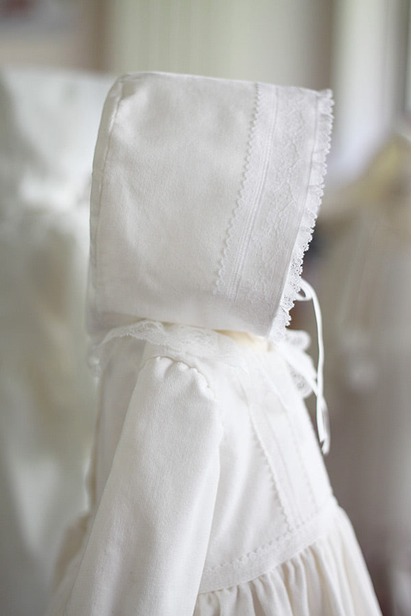 Bonnet de baptême bébé fille Angelina. Bonnet pour l'hiver en velours de coton et dentelle de Calais, doublé polaire. Création française Fil de Légende. Photo du bonnet vu de côté.