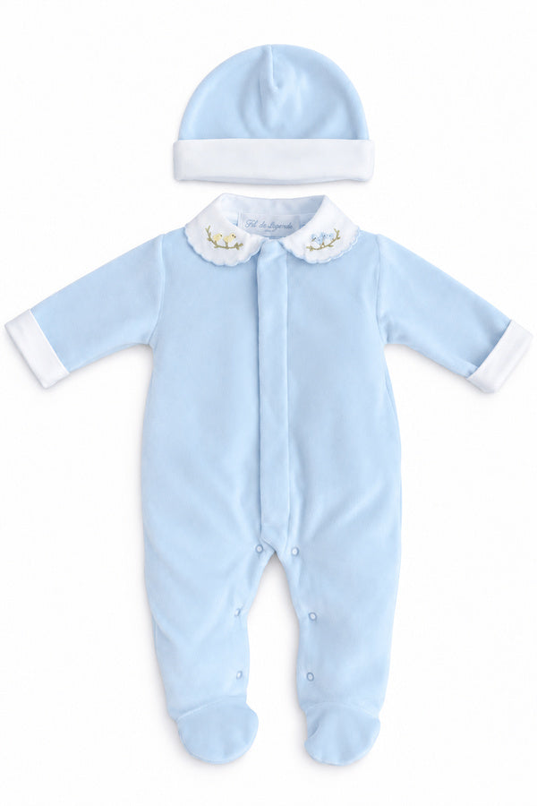 Ensemble de naissance bébé garçon Elio en velours de coton bleu ciel, composé d’un pyjama à col blanc brodé de petits oiseaux et d’un bonnet assorti à revers blanc. Pyjama personnalisable avec un petit ours bleu brodé et le prénom du bébé.